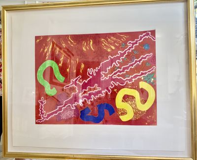 A framed abstract print in red, yellow, green and blue behind glass