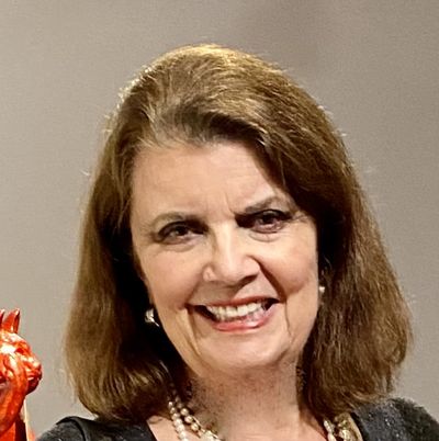 Suzanne Staley smiling, in a black top and pearls
