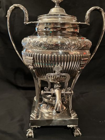 A sterling silver hot water urn with a spigot and paw feet