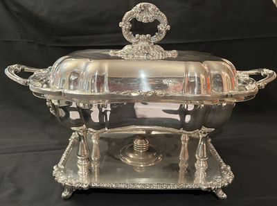 A sterling silver covered chafing dish on a footed stand with a burner