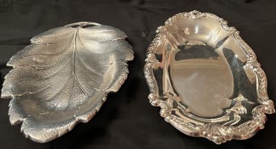 A sterling silver leaf-form dish beside an oval repousse serving bowl