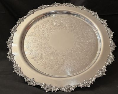A large sterling silver tray with an engraved centre and a cast floral rim