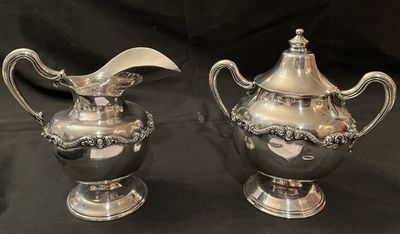 A sterling silver creamer and covered sugar bowl with scrolled handles